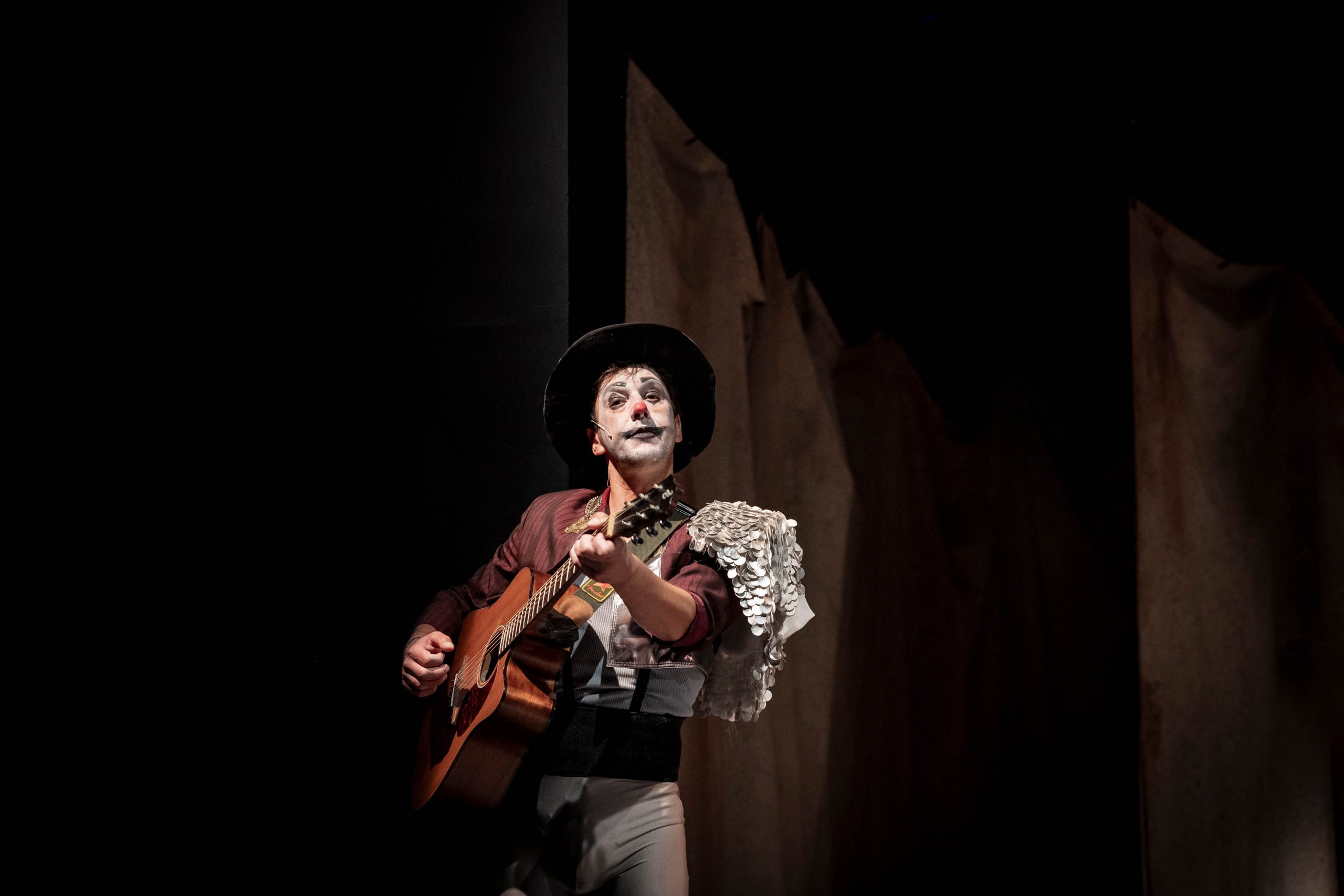 Ein Clown spielt Gitarre.