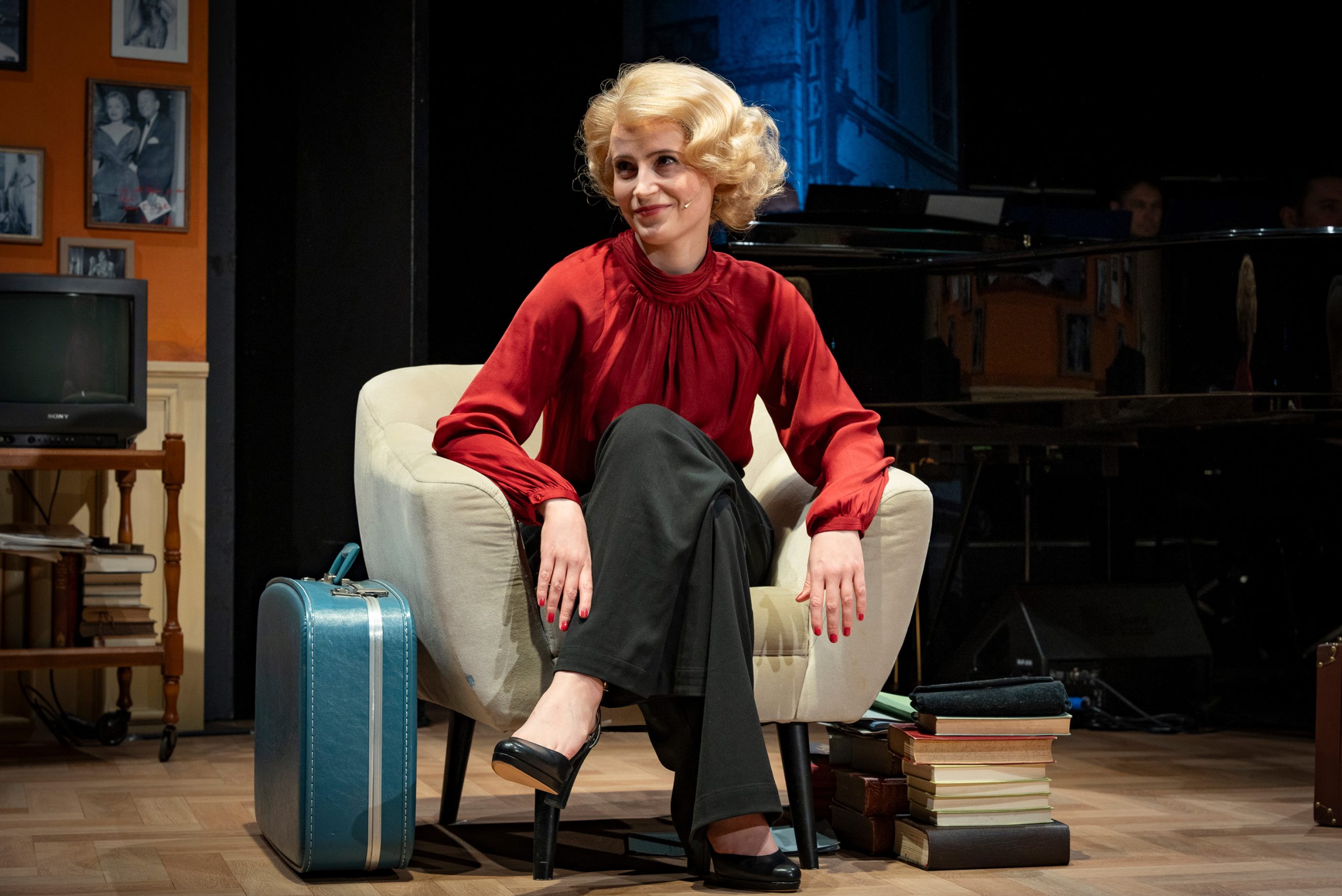 Maria Riva noch mit Marlene Perücke sitzt in einem Sessel.